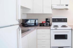 a white kitchen with a microwave and a stove at Sandman Hotel Penticton in Penticton