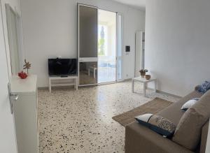 a living room with a couch and a television at Appartamento SOLE in Villa Giulia sul Mare in Marausa