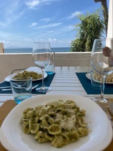 a plate of food on a table with wine glasses at Appartamento SOLE in Villa Giulia sul Mare in Marausa