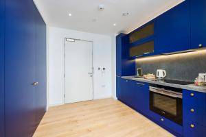 a kitchen with blue cabinets and a wooden floor at Apartment Near Canary Wharf 02 Arena & Excel in London