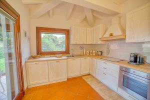 a large kitchen with white cabinets and a window at Villa Hibiscus Stintino in Stintino
