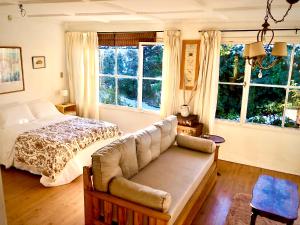 a bedroom with a bed and a couch and windows at Casita excelente ubicación in San Carlos de Bariloche