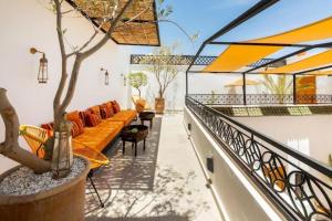 un patio al aire libre con sofás naranjas y un árbol en Riad Olika, en Marrakech