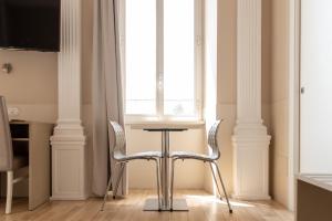 - une table et deux chaises dans une chambre avec fenêtre dans l'établissement Domus Porta Angelica, à Rome