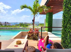 a young girl laying on a pink chair next to a pool at Sofía Boutique Condos by Bunik in Playa del Carmen