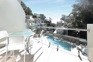 un balcone con tavolo, sedie e piscina di The Cove Noosa - Apartment 20 a Noosa Heads