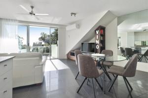 un soggiorno con tavolo, sedie e divano di The Cove Noosa - Apartment 20 a Noosa Heads
