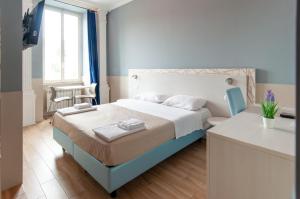 - une chambre blanche et bleue avec un lit et un bureau dans l'établissement Domus Porta Angelica, à Rome
