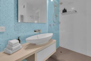 un bagno con lavandino bianco e piastrelle blu di The Cove Noosa - Apartment 21 a Noosa Heads Altre 3 foto