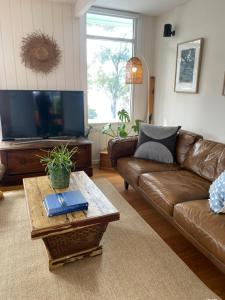 Sala de estar con sofá de cuero marrón y mesa de centro en Beach House, Stunning Views of Kingston Beach, en Kingston Beach