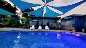 een zwembad met twee stoelen en een parasol erover bij Hidden Palms Inn in san juan la union