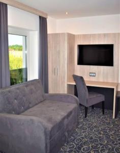 a living room with a couch and a desk with a television at Hotel Business Bay das ehemalige Staycation Hotel in Sindelfingen