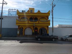 un camión estacionado frente a un edificio amarillo en Hotel Kiko, en Mazatlán