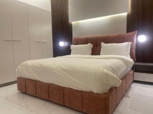 uma cama grande com uma cabeceira castanha num quarto em فلل بيات الفيصل Bayat Al Faisal Villas em Baljurashi