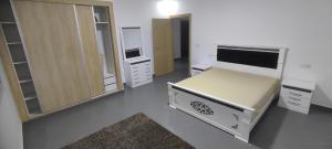 een slaapkamer met een bed en een televisie en kasten bij Logement familial in Selouane
