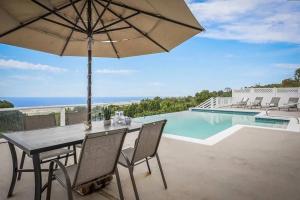 a table with an umbrella and a swimming pool at Oceanview Luxury Villa Pool & SPA in Kailua-Kona