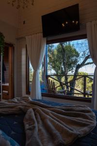 Un dormitorio con una cama y una ventana grande en Caminhos da Esmeralda, en Urubici