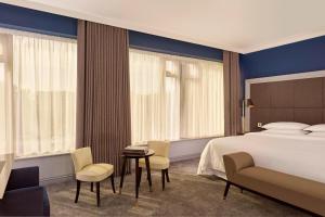 ヒリンドンにあるシェラトン ヒースロー ホテルのベッド、テーブル、椅子が備わるホテルルームです。