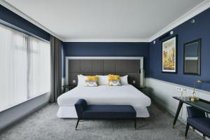 una camera da letto con un grande letto bianco e pareti blu di Sheraton Heathrow Hotel a Hillingdon