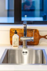 a sink with a bottle of soap sitting on top of it at Charming Downtown hideaway 1 bed 1 bath in Christchurch