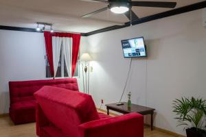 salon z czerwonym krzesłem i telewizorem z płaskim ekranem w obiekcie Zely Home #2 w mieście Cancún