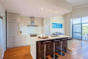 una cocina con armarios blancos y una isla con taburetes. en Eagle Escape I Private Properties, en Dunsborough