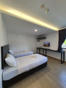 una camera con due letti e una scrivania di E Hotel a Kulim