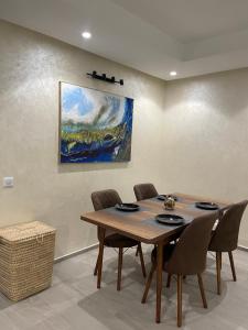 een eettafel met stoelen en een schilderij aan de muur bij Blue Apartment vue sur l’océan : Taghazout bay in Taghazout