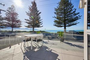 a table and chairs on a patio with trees at Kaikoura Waterfront Apartments in Kaikoura