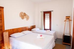 two beds in a room with white walls at Casa Aeolus in Camocim