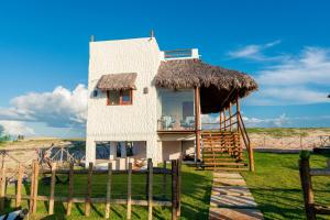 a small white house with a thatch roof at Casa Aeolus in Camocim