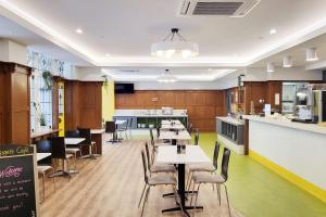 a restaurant with tables and chairs and a kitchen at ibis Styles Kingsgate Hotel in Melbourne