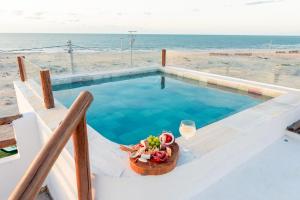 a swimming pool with a bowl of food and a glass of wine at Casa Aeolus in Camocim