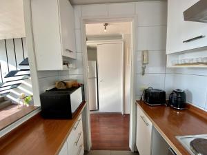 a kitchen with white cabinets and a black microwave at Loft Panoramico - Santiago in Santiago