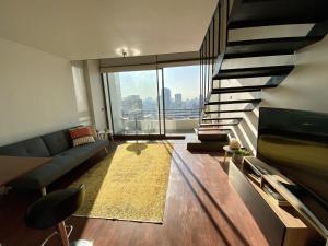 a living room with a couch and a large window at Loft Panoramico - Santiago in Santiago