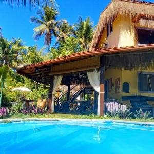 a house with a swimming pool next to a resort at Pousada Vila Mato Verde in Morro de São Paulo