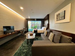 a living room with a couch and a bed and a television at NAI YA Hotel -SHA Extra Plus in Chiang Rai