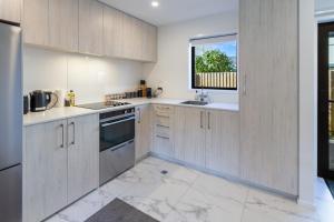 a kitchen with wooden cabinets and a window at Vibrant Central Christchurch Pad 2 bed 1 bath in Christchurch +20 photos
