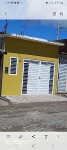uma casa amarela com portas brancas numa rua em Casa Confortável em Caruaru