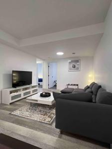 a living room with a black couch and a tv at Cozy Retreat - Basement Hideaway - Closest to Banff in Calgary in Calgary