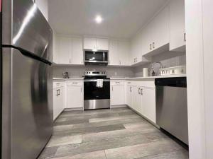 a stainless steel refrigerator in a kitchen with white cabinets at 2BR Suite, Private Entry, Full Kitchen, Washer & Dryer, Free Parking, Smart TV with Netflix, High-Speed Wi-Fi, Self Check-In, Near Banff National Park in Calgary