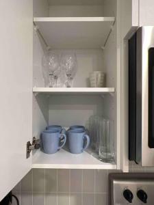 un armario con dos tazas y copas de vino en Cozy Retreat - Basement Hideaway - Closest to Banff in Calgary, en Calgary