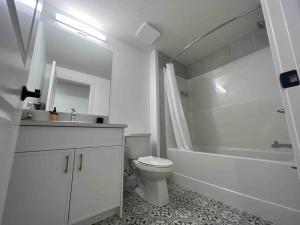 La salle de bains blanche est pourvue de toilettes, d'une baignoire et d'un lavabo. dans l'établissement Cozy Retreat - Basement Hideaway - Closest to Banff in Calgary, à Calgary