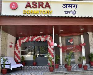 a store front with a red and white sign and plants at ASRA DORMITORY For Male And Female in Mumbai
