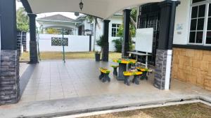 a patio with three tables and benches in front of a building at Rosspine Homestay in Jitra