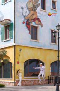 una pintura de una mujer y un hombre frente a un edificio en Khách sạn Chìa Khóa Vàng - Miễn phí tour xe điện tham quan Địa Trung Hải - TT Hoàng Hôn, en Phu Quoc