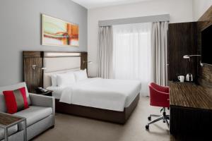 um quarto de hotel com uma cama branca e uma cadeira em Holiday Inn Express Dubai Internet City by IHG no Dubai