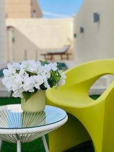 a yellow vase with white flowers sitting on a table at ِALMABEET Resort in Sinādil