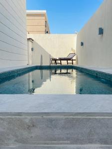 a swimming pool with a bench next to a building at ِALMABEET Resort in Sinādil