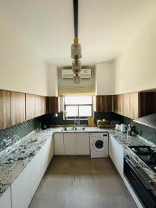 a kitchen with a sink and a washing machine at ِALMABEET Resort in Sinādil